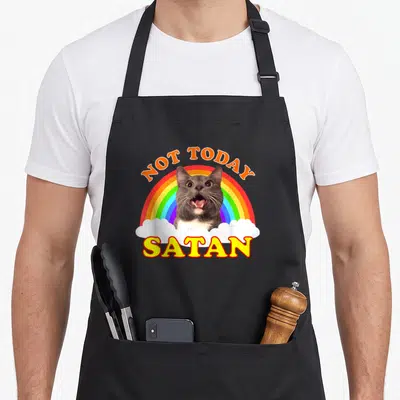 Tablier de cuisine noir avec un chat gris criant sous un arc-en-ciel et les mots Not Today Satan imprimés en lettres colorées.