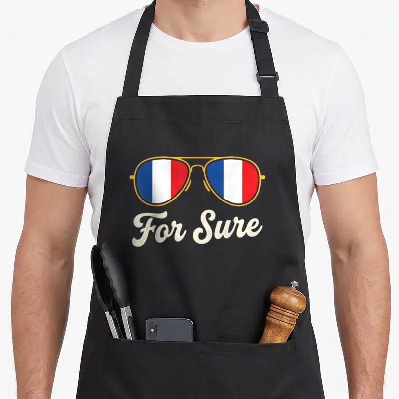 Tablier de cuisine noir avec lunettes de soleil aux verres tricolores et texte For Sure en bas.