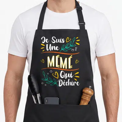 Tablier de cuisine noir avec l'inscription Je Suis Une Mémé Qui Déchire en blanc et jaune, orné de cœurs et de feuilles vertes.