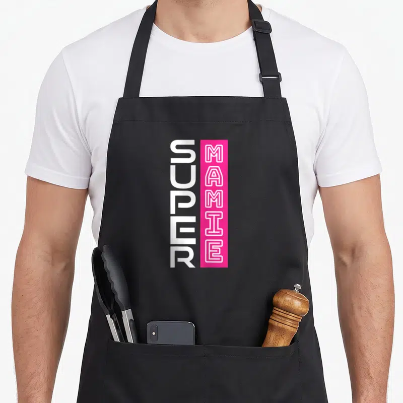 Tablier de cuisine noir avec inscription Super Mamie en lettres blanches et roses verticales.