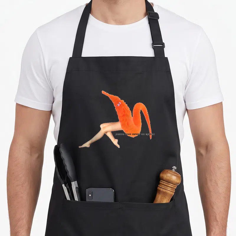 Tablier de cuisine noir avec ver orange sur jambes humaines et texte peace was never an option imprimé au centre.