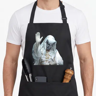 Tablier de cuisine noir avec statue à masque argenté King Baldwin levant la main droite en signe de salut ou de bénédiction.