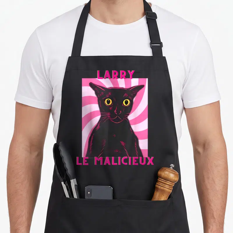 Tablier de cuisine noir avec illustration rose d'un chat noir nommé Larry le malicieux aux yeux jaunes.