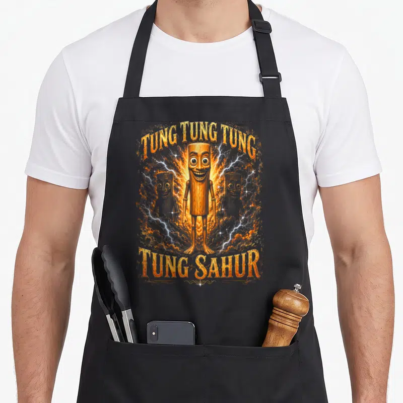 Tablier de cuisine noir avec illustration orange Tung Tung Tung Sahur et personnages en bois entourés d'éclairs.