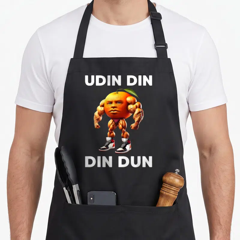 Tablier de cuisine noir avec un personnage orange musclé et des baskets imprimés au centre.