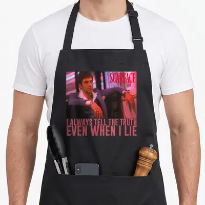 Tablier de cuisine noir avec une illustration de Scarface et le texte I ALWAYS TELL THE TRUTH EVEN WHEN I LIE en rose.