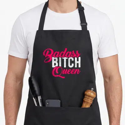 Tablier de cuisine noir avec l'inscription Badass Bitch Queen en rose et blanc.