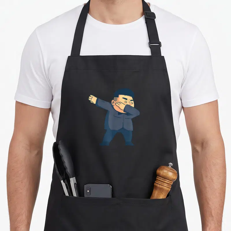 Tablier de cuisine noir avec une illustration de Kim Jong Un en train de faire le mouvement dab.
