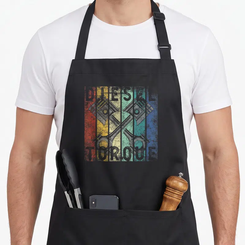 Tablier de cuisine noir avec deux pistons croisés et texte Distressed Diesel Torque sur bandes colorées.