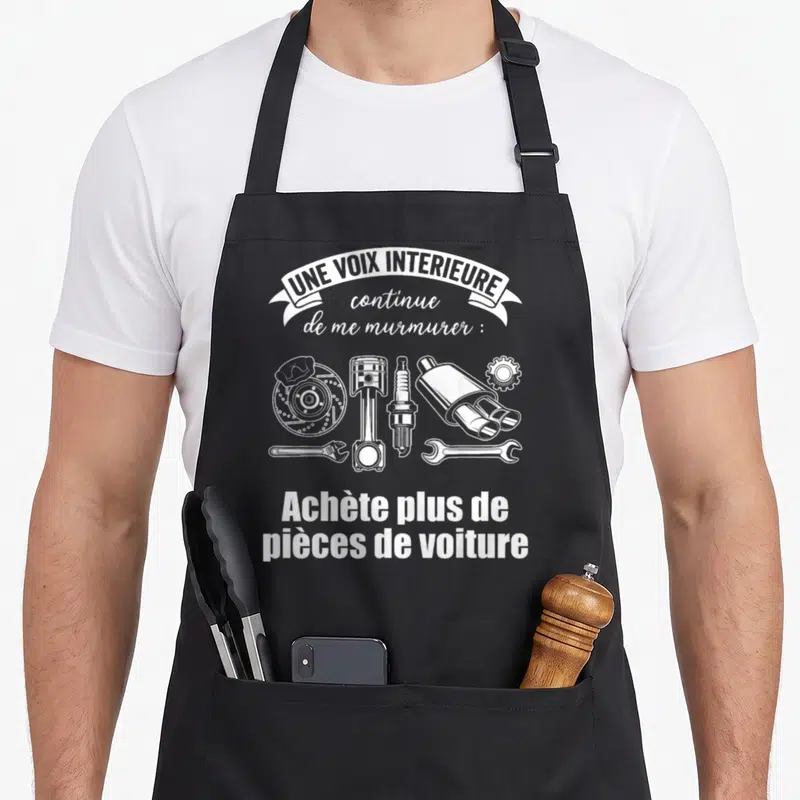 Tablier de cuisine noir avec inscription blanche « Achète plus de pièces de voiture » entourée d'un piston, d'une échelle et d'un silencieux.