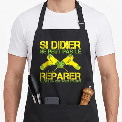 Tablier de cuisine noir avec deux perceuses jaunes croisées et le texte Si Didier ne peut pas le réparer alors on est tous foutus en jaune et vert.
