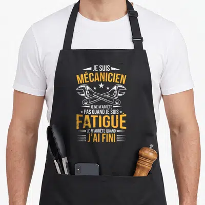 Tablier de cuisine noir avec inscription Je suis mécanicien et deux clés à molette blanches croisées en illustration centrale.