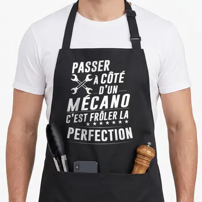 Tablier de cuisine noir avec texte blanc et deux clés croisées illustrant l'humour mécanique.
