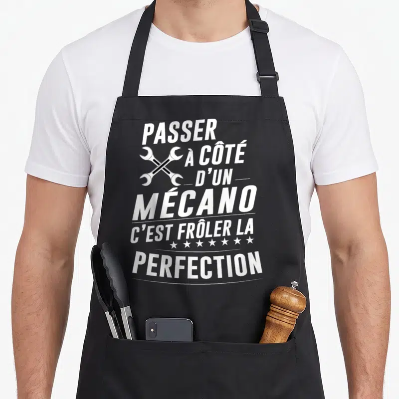Tablier de cuisine noir avec texte blanc et deux clés croisées illustrant l'humour mécanique.