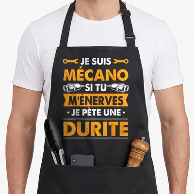 Tablier de cuisine noir avec inscription orange et blanche Je suis mécano si tu m'énerves je pète une durite orné de clés et de pots d'échappement.