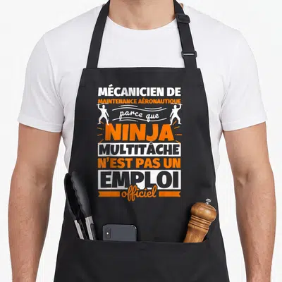 Tablier de cuisine noir avec texte blanc et orange évoquant un ninja multitâche en maintenance aéronautique.