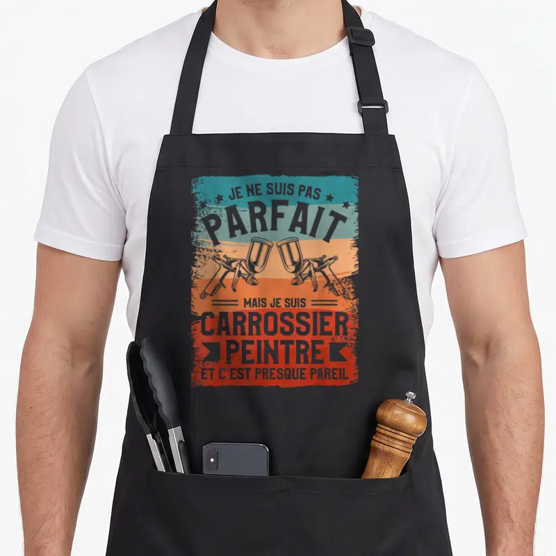 Tablier de cuisine noir avec deux pistolets à peinture croisés sur un fond aux couleurs bleu orange et rouge vif.