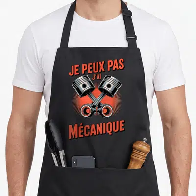 Tablier de cuisine noir avec deux pistons métalliques croisés et texte rouge Je peux pas j'ai mécanique