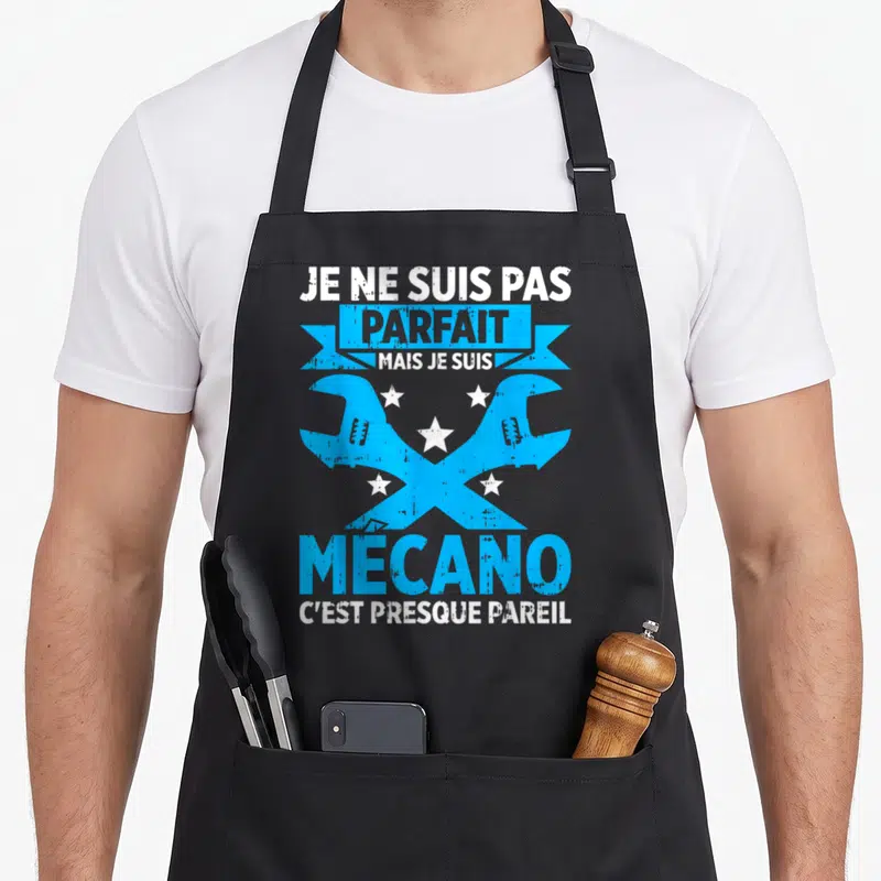 Tablier de cuisine noir avec deux clés croisées bleues et le texte Je ne suis pas parfait mais je suis Mécano en blanc.