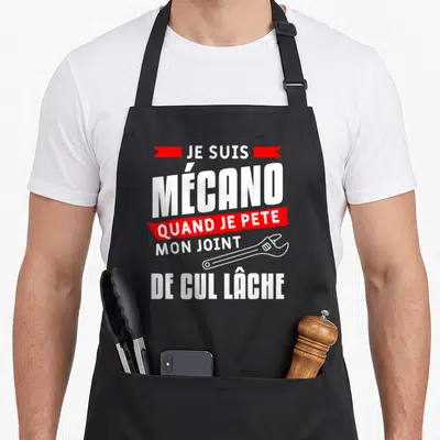 Tablier de cuisine noir avec inscription blanche et rouge Je suis mécano quand je pete mon joint de cul lâche accompagnée d'une clé.