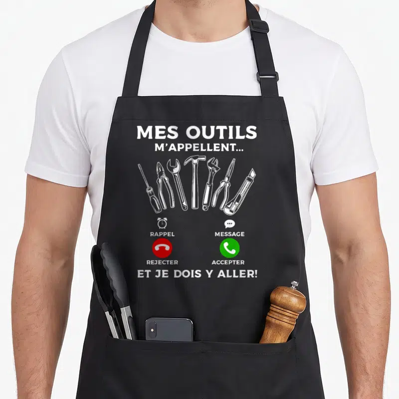 Tablier de cuisine noir avec illustration d'outils et interface de téléphone affichant Mes outils m'appellent et je dois y aller.