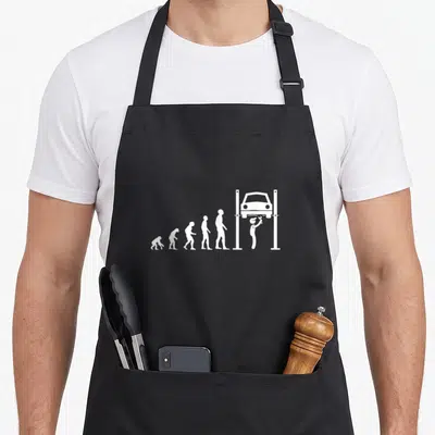 Tablier de cuisine noir avec illustration blanche montrant l'évolution de l'homme en mécanicien sous voiture levée.