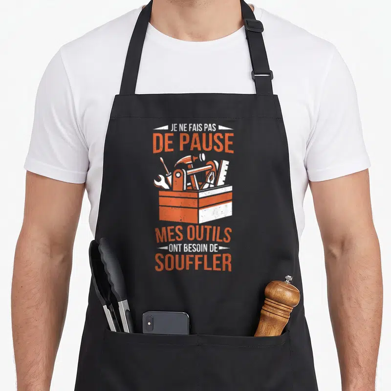 Tablier de cuisine noir avec une illustration de boîte à outils orange et texte humoristique sur les pauses.
