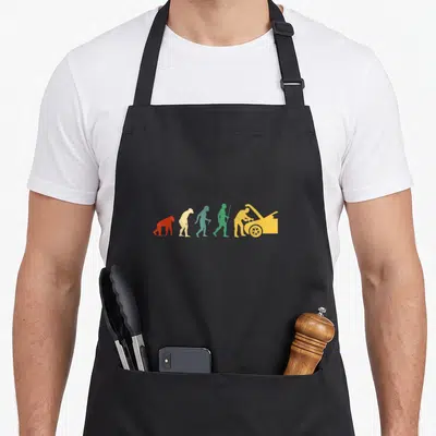 Tablier de cuisine noir avec illustration évolutive d'un homme transformé en mécanicien devant une voiture jaune.