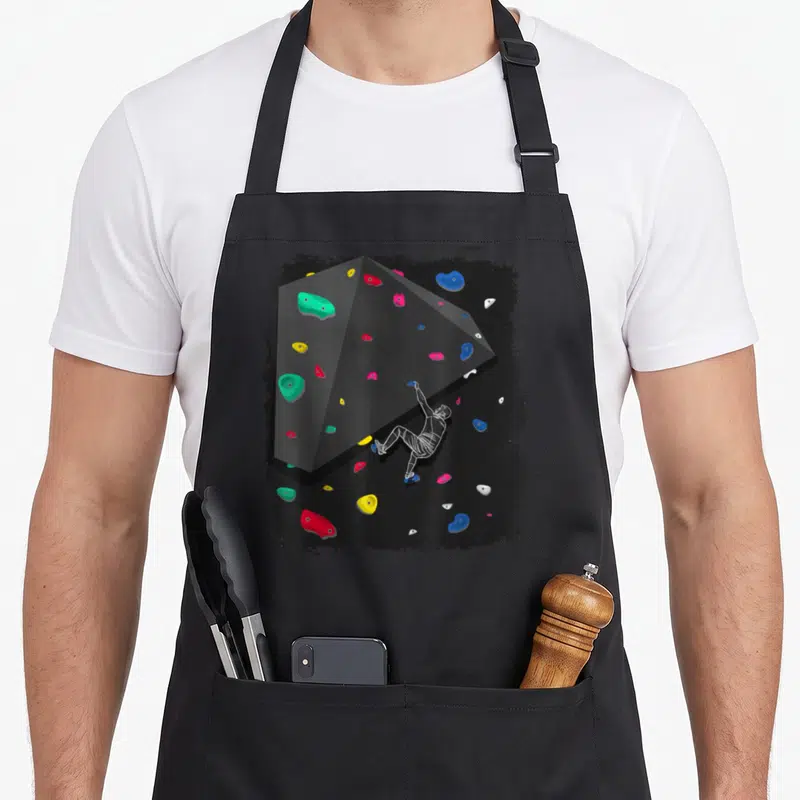 Tablier de cuisine noir avec illustration d'un bloc d'escalade aux prises multicolores et d'un grimpeur en silhouette blanche.