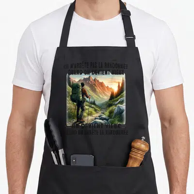 Tablier de cuisine noir avec un randonneur regardant des montagnes et le texte on n'arrête pas la randonnée quand on devient vieux.