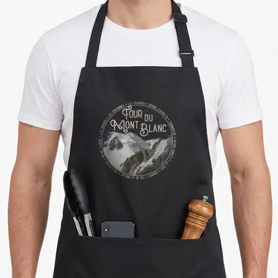 Tablier de cuisine noir avec un motif circulaire représentant les sommets du Tour du Mont Blanc et les noms des refuges traversés.
