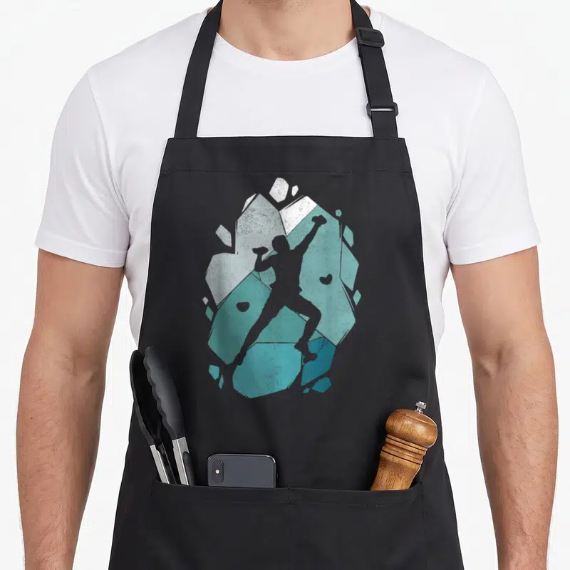 Tablier de cuisine noir avec une illustration stylisée d'un grimpeur boulder sur des formes géométriques turquoise et grises.