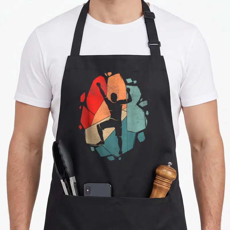 Tablier de cuisine noir avec silhouette de grimpeur et blocs d'escalade colorés en rouge orange et vert.