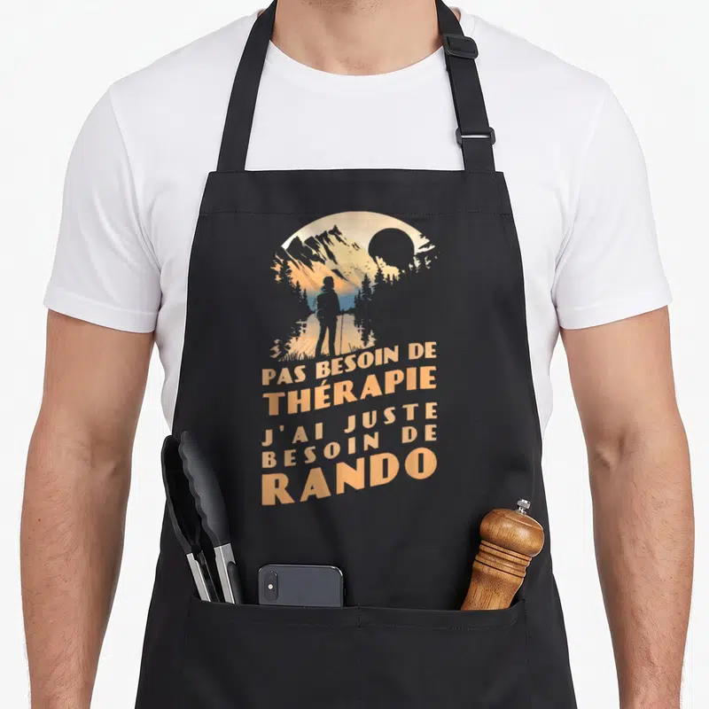 Tablier de cuisine noir avec silhouette de randonneur et texte orange sur fond de montagnes