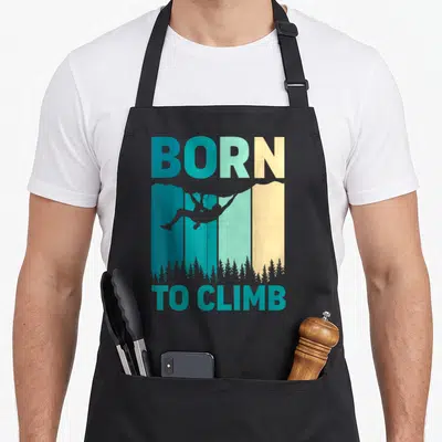 Tablier de cuisine noir avec silhouette de grimpeur et texte Born to Climb sur fond de montagnes colorées.