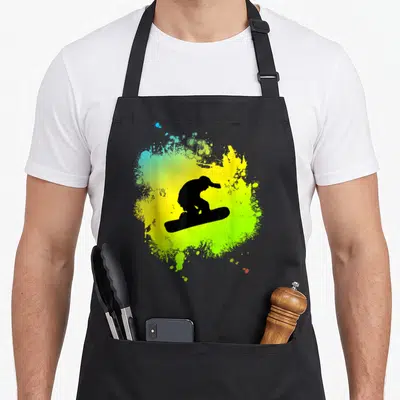 Tablier de cuisine noir avec silhouette de snowboarder sur fond d'éclaboussures jaune et vert vif.