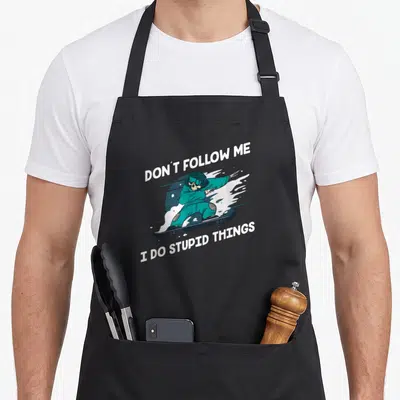 Tablier de cuisine noir avec illustration d'un squelette en train de faire du snowboard en tenue turquoise.