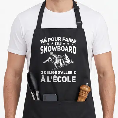 Tablier de cuisine noir avec inscription blanche et illustration d'un snowboardeur devant des montagnes.
