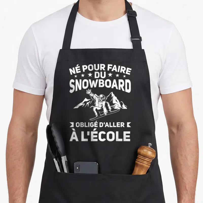 Tablier de cuisine noir avec inscription blanche et illustration d'un snowboardeur devant des montagnes.