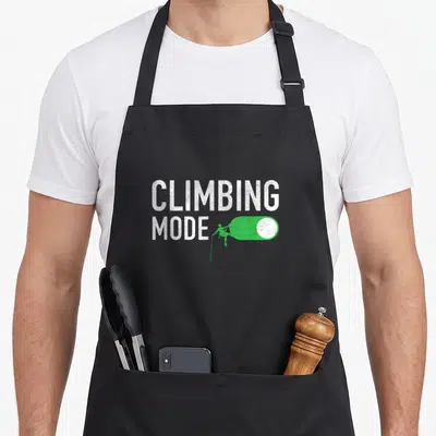 Tablier de cuisine noir avec inscription Climbing Mode et icône slider vert représentant un grimpeur.