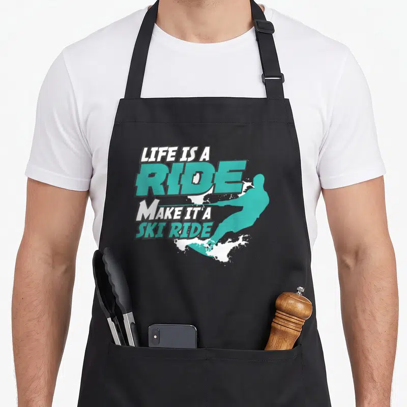 Tablier de cuisine noir avec inscription Life is a Ride Make it a Ski Ride et silhouette turquoise de skieur.