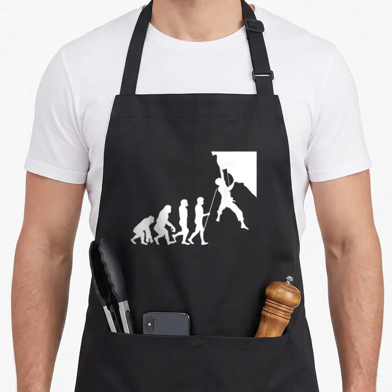 Tablier de cuisine noir avec une illustration blanche représentant l'évolution humaine se terminant par un silhouetté d'escaladeur accroché à la paroi.