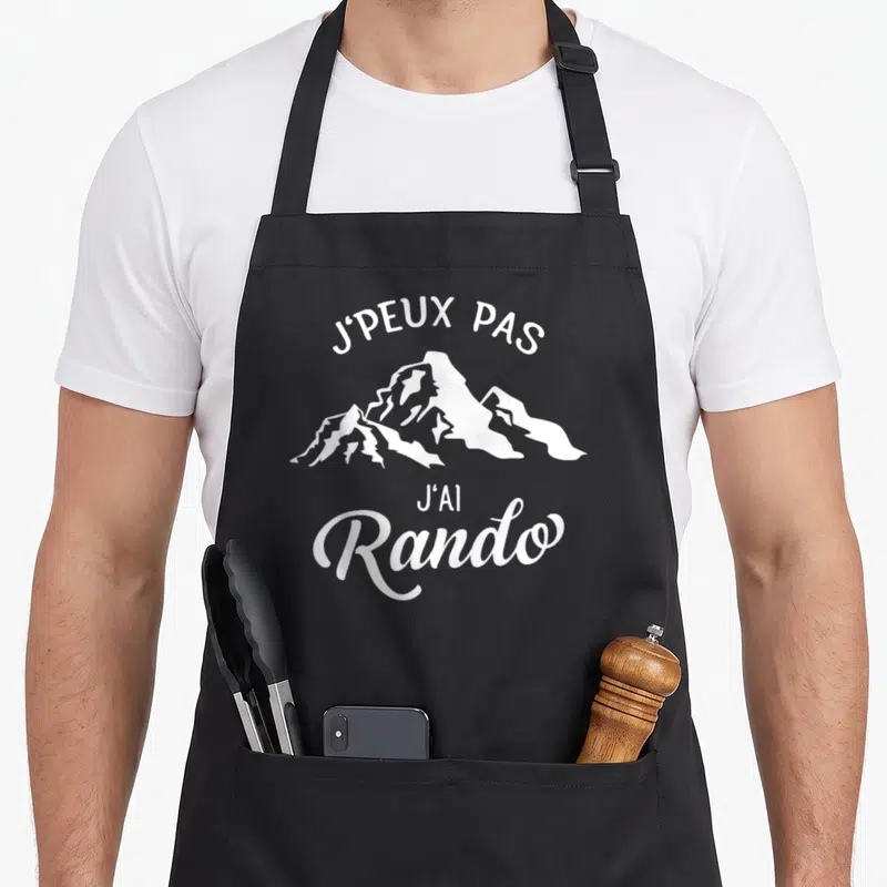 Tablier de cuisine noir avec inscription Je peux pas j'ai rando et silhouette de montagne blanche.