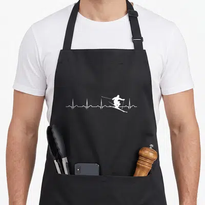 Tablier de cuisine noir avec un motif blanc représentant une ligne d'EKG traversée par la silhouette d'un skieur en pleine descente.