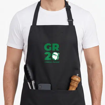 Tablier de cuisine noir avec logo vert GR 20 Corsica France et silhouette de randonneur stylisée dans le chiffre deux.
