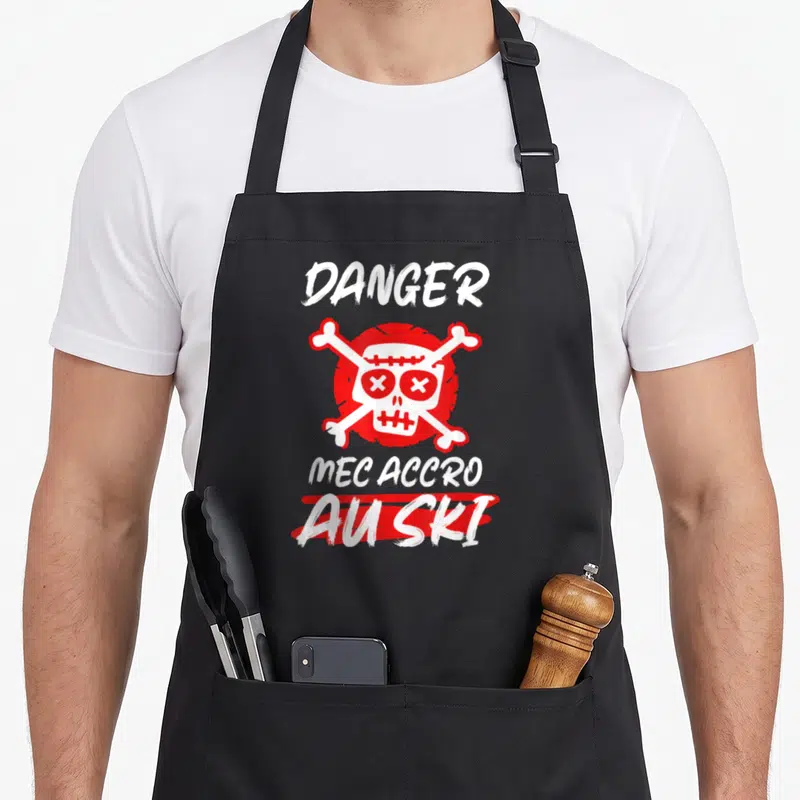 Tablier de cuisine noir avec un crâne rouge et l'inscription Danger Mec Accro Au ski en lettres blanches.