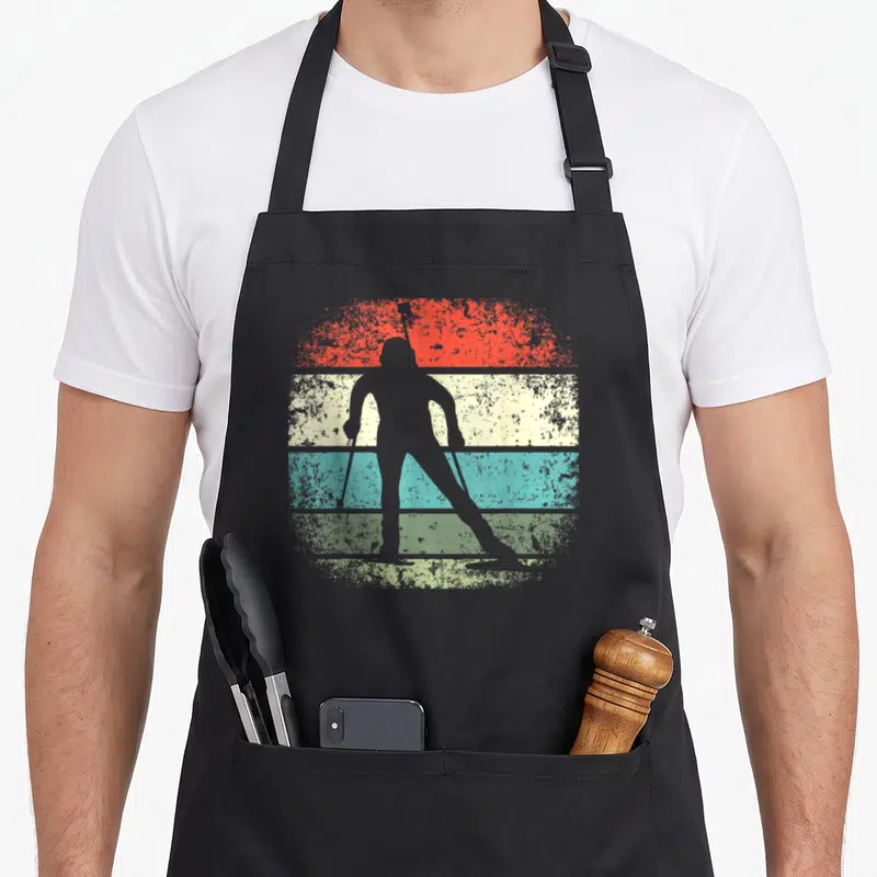 Tablier de cuisine noir avec silhouette de biathlète sur bandes colorées style rétro.