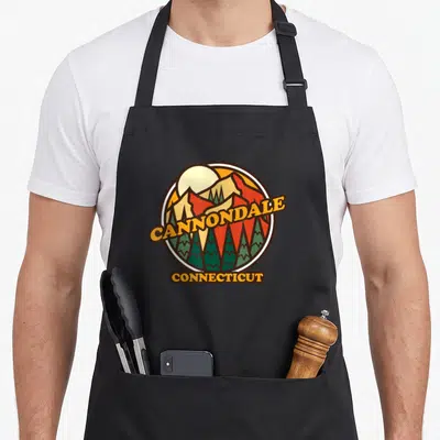 Tablier de cuisine noir avec un logo circulaire vintage représentant des montagnes et des arbres avec les mots Cannondale Connecticut.