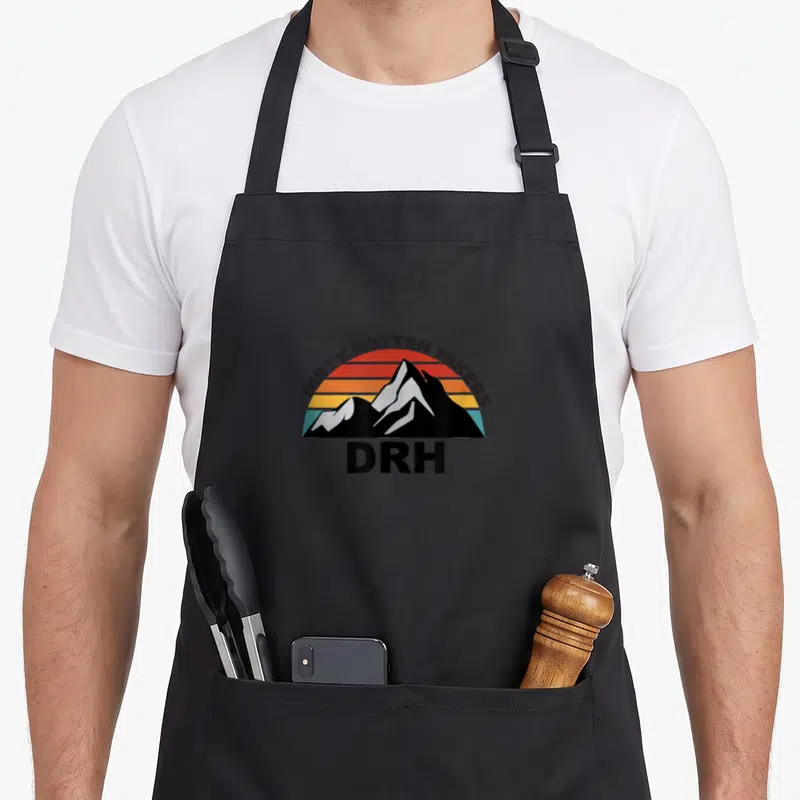 Tablier de cuisine noir avec un logo de montagnes aux couleurs vintage et l'inscription Dirty Rotten Hikers DRH.