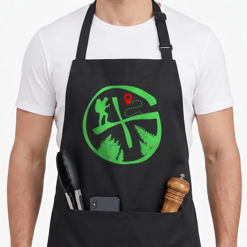 Tablier de cuisine noir avec un logo circulaire vert montrant un randonneur et une icône de localisation rouge.